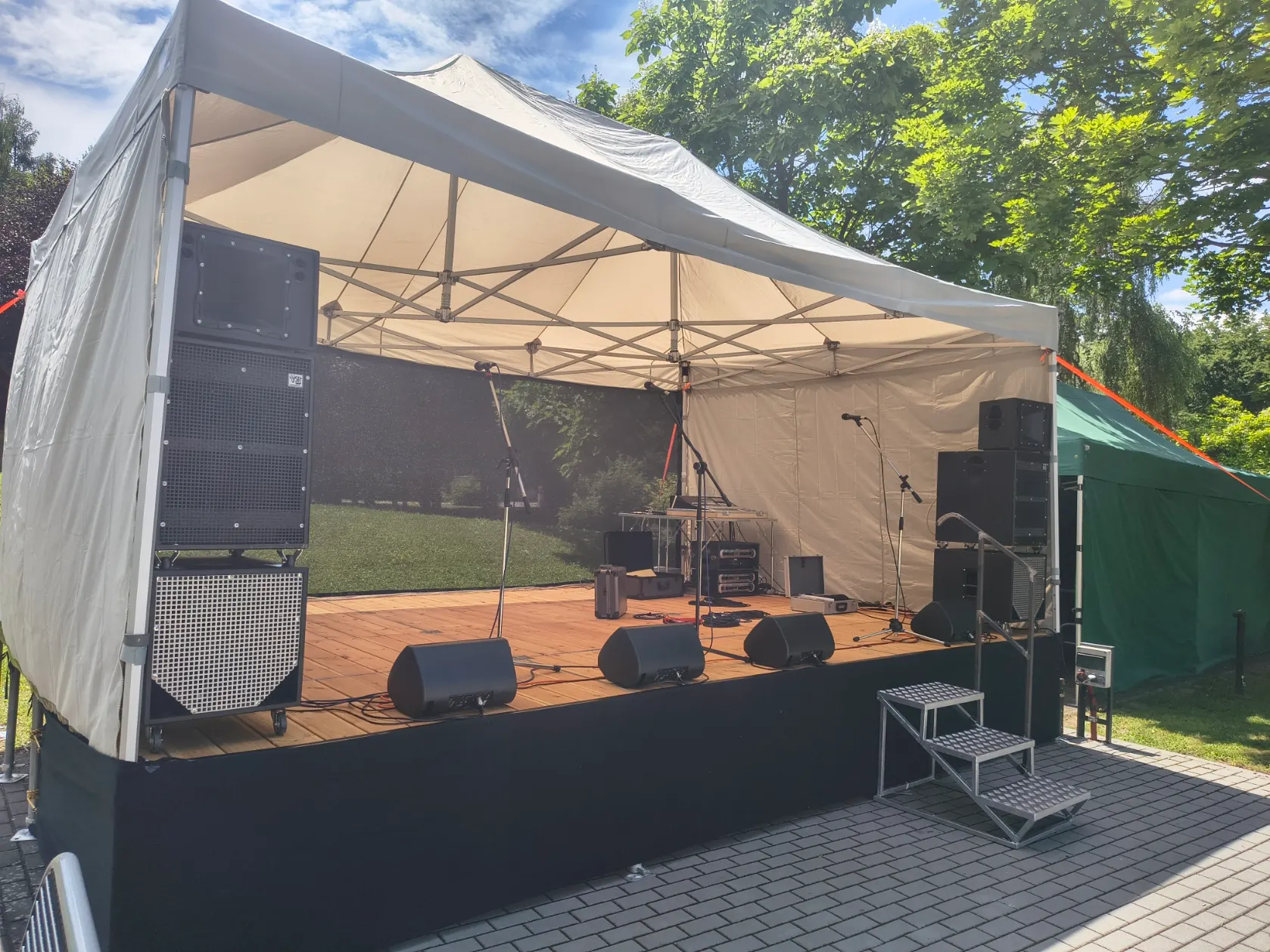 Pódium z boku — reprosoustavy, odposlechy a mikrofonní stojany